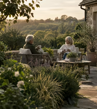 Two clients sitting with coffee on the stone terrace of their finished garden.